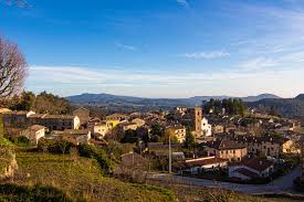 Fontanero Alpens: vista de una calle empedrada con casas de piedra y montañas al fondo en un día soleado.