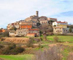Fontanero Argençola calle empedrada con casas de piedra antigua y montañas al fondo en un día soleado