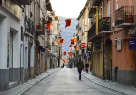 Fontanero Bagà reparando tubería frente al pintoresco casco antiguo empedrado bajo el arco medieval.