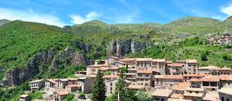 Fontanero Castellar de n'Hug: Calle estrecha empedrada con casas de piedra y montañas al fondo, típico pueblo rural.