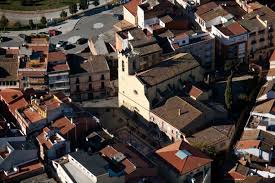 Fontanero Castellbisbal reparando tubería en una calle adoquinada con casas coloridas de estilo tradicional catalán