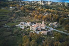 Fontanero Fígols, calle tranquila con casas de piedra y montañas al fondo en un entorno rural pintoresco.