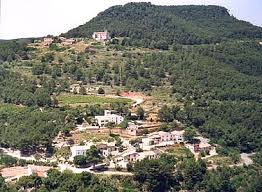 Fontanero Font-rubí: calle adoquinada con casas de piedra y paisaje montañoso al fondo