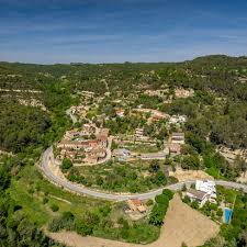 Fontanero Marganell trabajando cerca de una calle tranquila con casas tradicionales y vistas a las montañas.