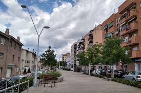 Fontanero Polinyà reparando tuberías en calle típica con casas de ladrillo y vegetación exuberante