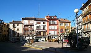 Fontanero Prats de Lluçanès: calle pintoresca con casas de piedra y paisajes verdes en el fondo.