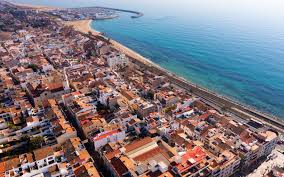 Fontanero Premià de Mar frente a casas blancas en calle pintoresca cerca del puerto local con cielo despejado.