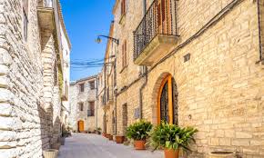 Fontanero Pujalt, calle empedrada con casas de piedra y montañas al fondo, típico del pueblo catalán.