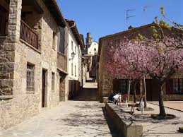 Fontanero Sant Boi de Lluçanès, calle pintoresca con casas antiguas y montañas al fondo en día soleado