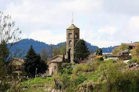 Fontanero Sant Vicenç de Torelló calle estrecha con fachadas de piedra y paisaje montañoso al fondo