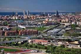 Fontanero Santa Coloma de Gramenet arreglando tuberías en calle típica con edificios de ladrillo y vegetación urbana