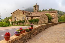 Fontanero Santa Maria de Besora reparando en calle céntrica con casas de piedra y montañas al fondo