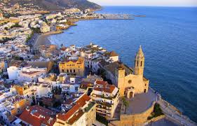 Fontanero Sitges reparando en la pintoresca calle del centro histórico con casas blancas y flores coloridas.