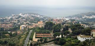 Vista de una calle tranquila en Tiana con un fontanero trabajando cerca de una antigua casa de piedra