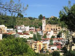 Fontanero Torrelles de Llobregat caminando por una calle tranquila con casas tradicionales y montañas al fondo
