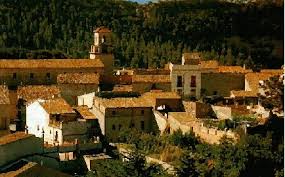 Fontanero Vallbona d'Anoia calle tranquila con casas de piedra y un fontanero trabajando en la puerta de una vivienda