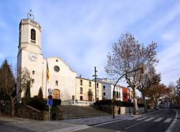 Fontanero Vallgorguina examina tuberías cerca del histórico Ayuntamiento en una soleada calle del pueblo catalán