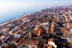 Fontanero Vilassar de Mar: vista de una calle con casas de estilo mediterráneo y palmeras bajo un cielo azul.